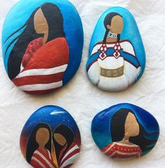 four painted rocks depicting native american people on white paper towel with red, white and blue background