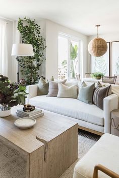 a living room filled with lots of furniture and plants on the wall above it's coffee table