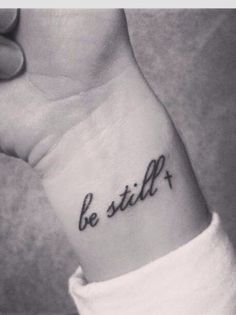 a black and white photo of a person's wrist with the word be still on it