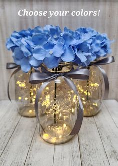 three mason jars filled with blue hydrangeas and lights that say choose your colors