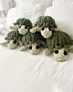 four crocheted stuffed animals sitting on top of a bed