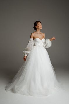 a woman in a white wedding dress with long sleeves and an off the shoulder top