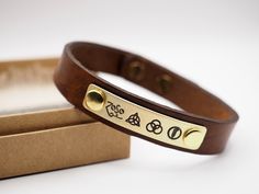 Brown Genuine Leather and Brass Plate This leather bracelet measures approximately 1/2 inch (1.3cm) in width. 📏SIZES:  6.5 inches = 16.5 cm 7    inches = 17.5 cm 7.5 inches = 19 cm 8    inches = 20 cm 8.5 inches = 21.5 Adjustable Brown Band Bracelet, Brown Adjustable Band Bracelet As Gift, Vintage Adjustable Leather Bracelet As Gift, Vintage Adjustable Leather Bracelet For Gift, Brown Adjustable Bracelets As Gift, Vintage Adjustable Leather Bracelet Gift, Adjustable Gold Leather Bracelet Engraved, Vintage Brown Wristband As Gift, Vintage Brown Wristband For Gift