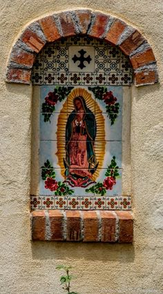 an image of the virgin mary in stained glass on a stucco wall with brick arch