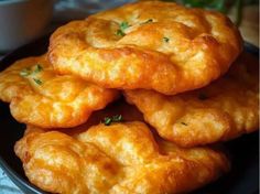 some fried food is stacked on top of each other in a black plate with sauce and parsley