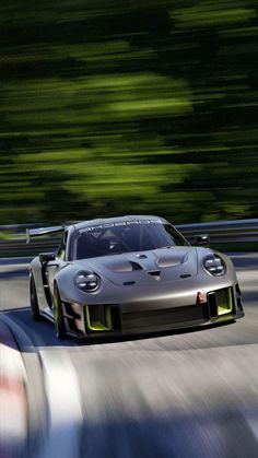 a silver race car driving on a track with blurry trees in the back ground