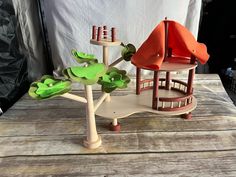 a wooden table topped with two small houses and green plants on top of each other