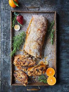 an assortment of food on a tray with oranges and other foods around it, including meat