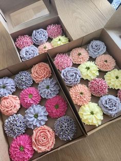 two boxes filled with different colored cupcakes on top of a wooden table next to each other