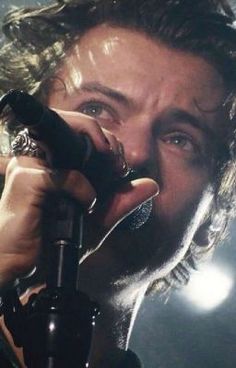 a close up of a person holding a microphone in his hand and looking at the camera