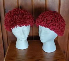 two white mannequin heads with red flowered hair on top of each head