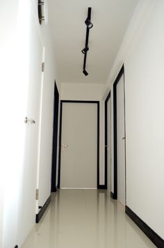 an empty hallway with white walls and black trim on the doors is seen in this image