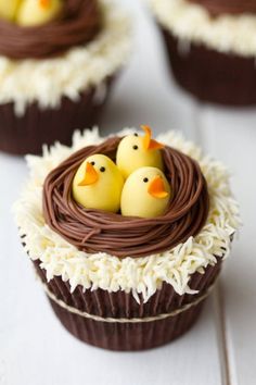 two cupcakes decorated with chocolate icing and rubber ducks in a nest on top of each other