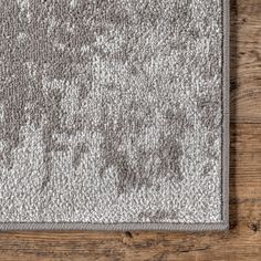 an area rug with grey and white designs on wood flooring, viewed from above