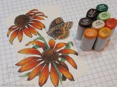 some markers are sitting on top of a piece of paper next to flowers and butterflies