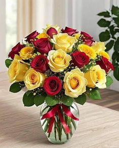 a vase filled with yellow and red roses