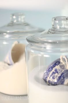 two glass jars with blue and white porcelain items in them