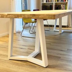 a wooden table sitting on top of a hard wood floor next to a book shelf