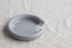 a small gray object sitting on top of a white cloth covered tablecloth with a spoon sticking out of it