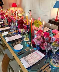 the table is set with flowers, candles and menus for an elegant dinner party