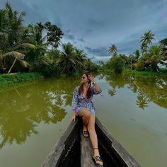 a woman sitting in the back of a boat on a body of water surrounded by palm trees