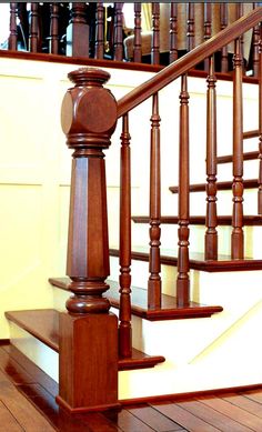 a wooden stair case next to a banister in a room with hard wood flooring