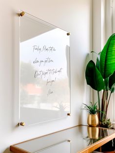 there is a large mirror on the wall above a table with a potted plant