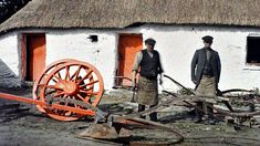 two men standing in front of a white building with an orange wheel on the ground