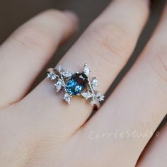 a woman's hand with a blue and white diamond ring on top of it