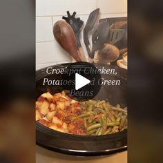 a crock pot with potatoes and green beans in it on a stove top next to other cooking utensils