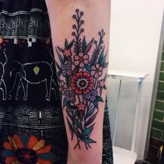 a woman's arm with flowers on it and an elephant in the back ground