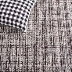 a black and white checkered pillow sitting on top of a gray carpeted floor