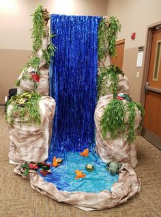 an indoor waterfall with fish and plants in the center, surrounded by blue streamers