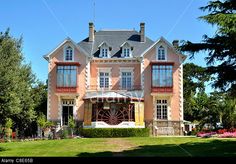 a large pink house sitting in the middle of a lush green field