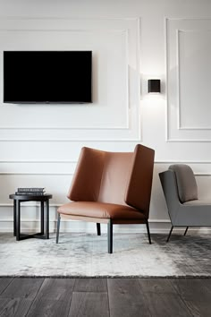 a living room with two chairs and a television on the wall