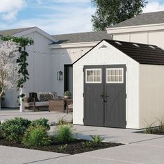 a small white shed sitting in the middle of a yard