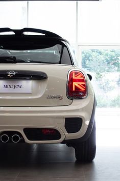 the back end of a mini jcw car in a showroom with large windows