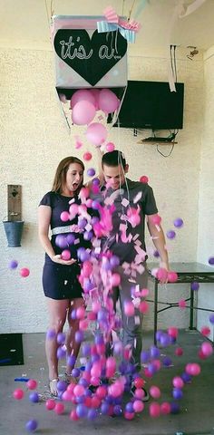 two people standing in front of a bunch of pink and purple balloons that say it's us