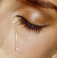 a woman's eye with water dripping from the top of her teary lashes