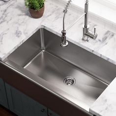 a stainless steel kitchen sink and faucet with marble counter tops in a home