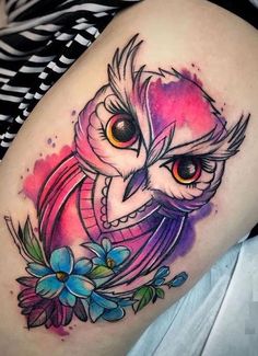 an owl tattoo on the thigh with watercolors and flowers around it's eyes