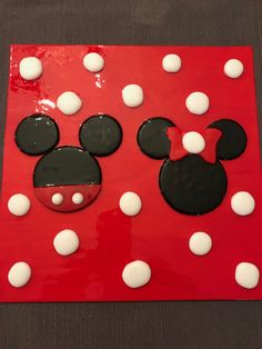 a mickey mouse cake with white and black icing on red square shaped paper plate