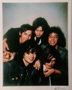 a group of young men standing next to each other in front of a white wall