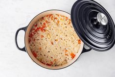 a pot filled with rice and carrots sitting on top of a white countertop