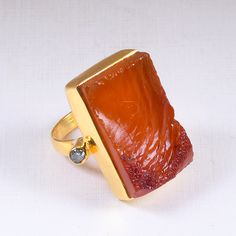 This is unique and one-of-a-kind ring with its natural raw red Carnelian stones and cubic zirconia set on a 22 karat yellow Gold plated artisan crafted ring. This adjustable ring is a coral wonder Being a color that matches any kind of skin tone and dress, you can tam this ring with any dress you want! Artisan Hand-crafted Ring, Natural Carnelian Ring, Rough Stone Ring, Bezel Set Stone Ring, Large Statement Ring, Modern Fashion Ring Product Details Item Code: BJBR-0003 Stone Name: Carnelian And Gold Carnelian Jewelry For Wedding, Yellow Gold Chalcedony Ring Gift, Unique Carnelian Ring Jewelry, Amber Rings With Gemstone Accents For Gifts, Gold Carnelian Ring Jewelry, Gold Carnelian Ring For Wedding, Carnelian Gold Wedding Rings, Yellow Gold Agate Rings For Gift, Gold Carnelian Ring For Anniversary