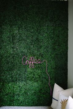 a bedroom with a green wall and white pillows on the bed, along with a pink string hanging from the headboard