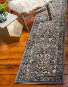 a long rug is on the floor next to a chair and table with a potted plant