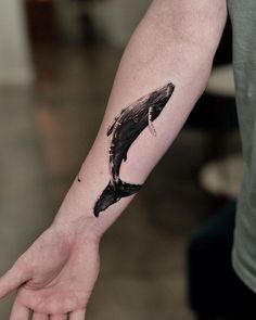 a person with a tattoo on their arm that has a whale in it's mouth