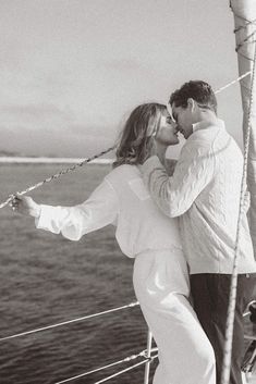 a man and woman kissing on the deck of a sailboat in black and white