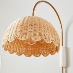 a wicker lamp hanging from a white wall